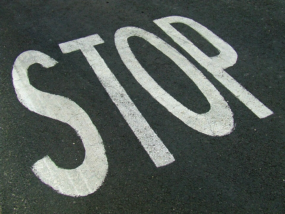 На фото изображена надпись STOP на асфальте.